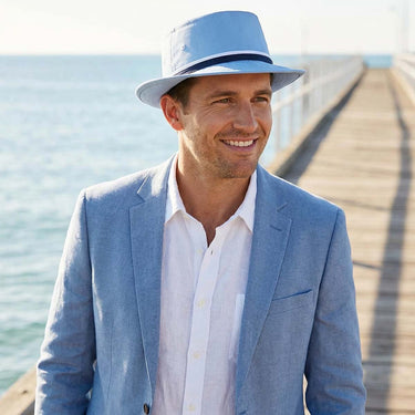 Man wearing a blue bucket hat on a pier with a blue blazer on.